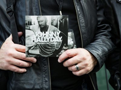 La couverture du dernier album posthume de Johnny Hallyday tenue par un homme à Paris le 15 octobre 2018 - Geoffroy VAN DER HASSELT [AFP/Archives]
