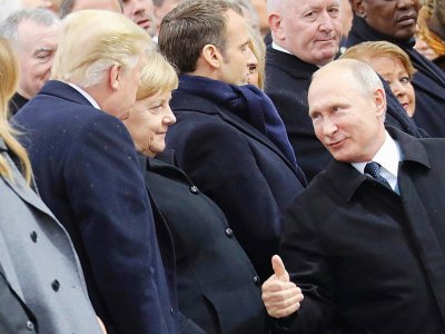 Le président russe Vladimir Poutine s'entretient avec son homologue américain Donal Trump, devant la chancelière allemande Angela Merkel, le 11 novembre 2018 à Paris. - ludovic MARIN [POOL/AFP]