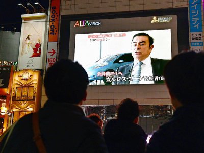Des passants regardent le 22 novembre 2018 à Tokyo la photo de Carlos Ghosn, patron de Renault-Nissan, arrêté pour soupçons de malversations financières et fraude fiscale - Kazuhiro NOGI [AFP/Archives]