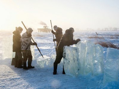 Des villageois en Iakoutie (nord-est de la Sibérie) extraient un bloc de glace qui les approvisionnera en eau douce pour l'hiver, le 27 novembre 2018 à Oï en Russie - Mladen ANTONOV [AFP]