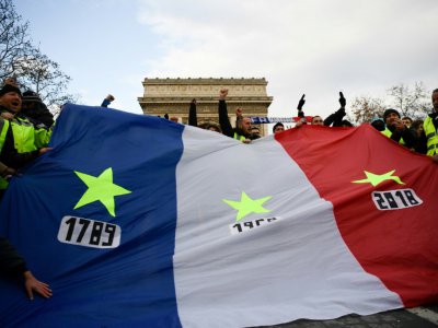 Des "gilets jaunes" brandissent un drapeau frappé d'étoiles et de trois dates : 1789, 1968, et 2018, à Paris, le 8 décembre 2018 - Bertrand GUAY [AFP]