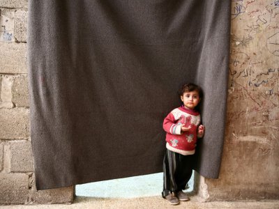 Un enfant syrien devant le rideau qui fait office de porte d'entrée aux chambres de déplacés syriens qui ont trouvé refuge dans une cave dans la ville d'Al-Bab (nord syrien), le 7 décembre 2018 - Nazeer AL-KHATIB [AFP]