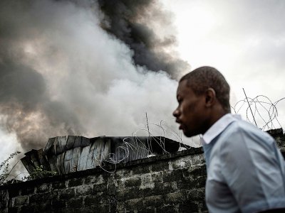 Un homme passe le 13 décembre 2018 à Kinshasa devant l'incendie qui a détruit une partie du matériel électoral pour la présidentielle dans la capitale de la République démocratique du Congo. - John WESSELS [AFP/Archives]