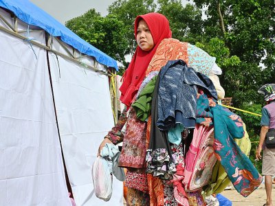 Une femme porte des vêtements donnés par un centre d'aide dans le village de Citangkil à Sumur, le 25 décembre 2018, trois jours après le tsunami qui a frappé l'Indonésie - Adek BERRY [AFP]