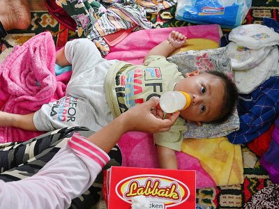 Un bébé boit du lait dans un centre pour personnes déplacées à Carita, dans la province de Banten, le 24 décembre 2018 en Indonésie - ADEK BERRY [AFP]