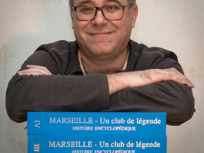 L'archiviste de Marseille Gilles Castagno avec son encyclopédie de quatre volumes sur le club le 4 décembre 2018 dans sa maison à Marseille - GERARD JULIEN [AFP/Archives]