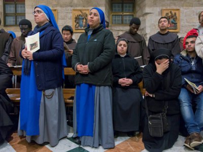 Des Chrétiens prient lors de la messe de minuit célébrée dans l'église Sainte-Catherine à Bethléem, le 25 décembre 2018 - Nasser Nasser [POOL/AFP]