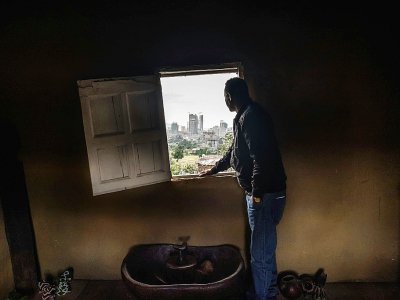 Berhanu Mengistuin regarde par la fenêtre de sa maison familiales les immeubles modernes à Addis Abeba, le 29 novembre 2018 en Ethiopie - EDUARDO SOTERAS [AFP]