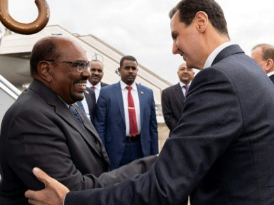 Le président syrien Bachar al-Assad (D) recevant son homologue soudanais Omar el-Béchir (G) à l'aéroport de Damas, le 16 décembre 2018 - STRINGER [SANA/AFP]