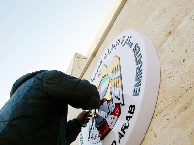 Un homme fixe l'emblème des Emirats arabes unis sur le mur de leur ambassade à Damas le 27 décembre 2018 - [AFP]