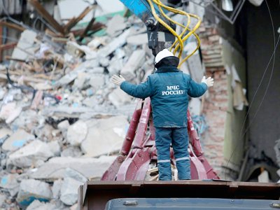 Un secouriste guide l'opérateur d'une grue qui enlève les gravats de l'immeuble partiellement effondré, le 2 janvier 2019 - STR [AFP]