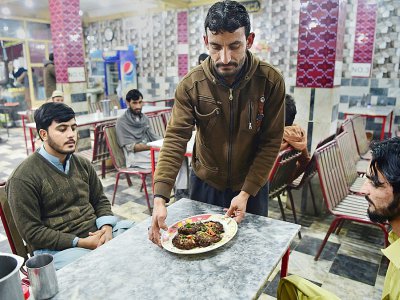 Un serveur apporte une assiette de kebabs à des clients du restaurant Tory Kebab House à Namak Mandi, dans le coeur gastronomique de Peshawar, le 13 décembre 2018 - ABDUL MAJEED [AFP]