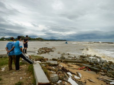 Des habitants regardent un bateau de pêche emporté par les fortes vagues suscitées par la tempête Pabuk dans le sud de la Thaïlande, le 4 janvier 2019 - STR [AFP]