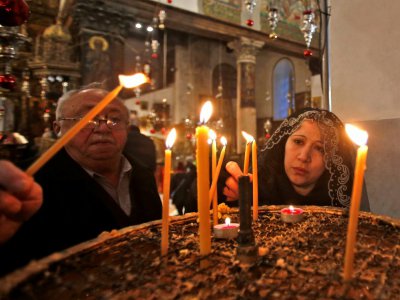 Des fidèles orthodoxes allument des bougies à l'intérieur de la Basilique de la Nativité, à Bethléem, en Cisjordanie occupée, à l'occasion du Noël orthodoxe, le 6 janvier 2019 - Musa AL SHAER [AFP]