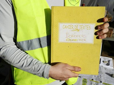 Un "gilet jaune" montre le cahier de doléances qu'il présente sur un rond-point à Cagnes-sur-mer, le 20 décembre 2018 - VALERY HACHE [AFP/Archives]