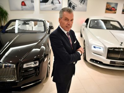 Le directeur général de Rolls-Royce, Torsten Müller-Ötvös pose entre un modèle de Rolls-Royce Dawn (g) un modèle Wraith Black Badge (d) dans le showroom du centre de Londres le 9 janvier 2019 2019 - Ben STANSALL [AFP]