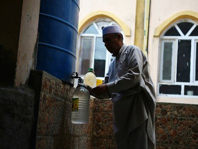 Un Afghan remplit d'eau des bouteilles en plastique au robinet d'une citerne, le 25 octobre 2018 à Kaboul - WAKIL KOHSAR [AFP]