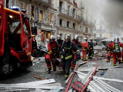 Des pompiers évacuent un blessé après une explosion dans une boulangerie, le 12 janvier 2019, rue de Trévise dans le 9e arrondissement de Paris - Thomas SAMSON [AFP]