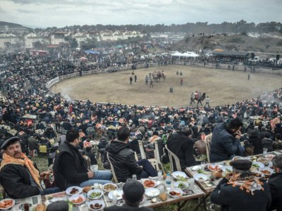 Des spectateurs installés à des tables piquent-niquent dans les gradins en assistant aux combats de chameaux à Selcuk, le 20 janvier 2019 en Turquie - BULENT KILIC [AFP]