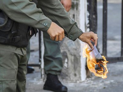 Un soldat brûle un exemplaire du texte de loi d'amnistie aux militaires soutenant le président autoproclamé Juan Guaido, devant l'entrée du quartier général de l'armée à Caracas, le 27 janvier 2019 - Yuri CORTEZ [AFP]