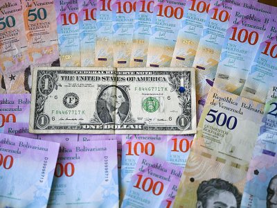 Des bolivars, la monnaie vénézuélienne, et un billet d'un dollar, à Caracas le 28 janvier 2019 - YURI CORTEZ [AFP]