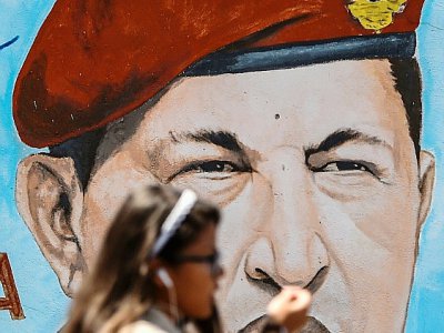 Une étudiante passe devant un portrait de l'ancien président vénézuélien Hugo Chavez, peint sur un mur, à Caracas le 29 janvier 2019 - Juan BARRETO [AFP]