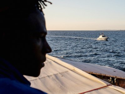 Un migrant regarde une vedette des autorités italiennes escorter le Sea Watch à son arrivée à Catane, le 31 janvier 2019 - FEDERICO SCOPPA [AFP]