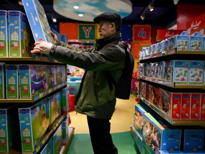 Un homme regarde un jouet Peppa Pig dans un magasin, le 25 janvier 2019 à Pékin - WANG Zhao [AFP/Archives]