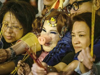L'actrice hongkongaise Lana Wong (au centre avec un groin de porc) se presse entre deux femmes devant un temple pour fêter le Nouvel An chinois ouvrant l'année du "cochon de terre", le 4 février 2019 à Hong Kong - Philip FONG [AFP]