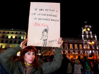 Une femme brandit une affiche représentant une oeuvre de Banksy lors d'une manifestation contre le parti espagnol d'extrême droite Vox, le 15 janvier 2019 à Madrid - GABRIEL BOUYS [AFP/Archives]