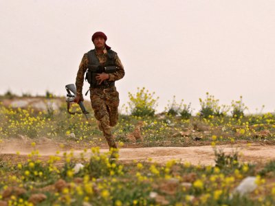 Un soldat des Forces démocratiques syriennes court avec son arme lors d'une opération contre le groupe Etat islamique, près de Baghouz en Syrie, le 14 février 2019 - Delil souleiman [AFP]