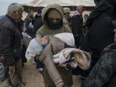 Un soldat des Forces démocratiques syriennes porte un enfant dont la famille a fui le groupe Etat islamique, à Baghouz en Syrie, le 14 février 2019 - Fadel SENNA [AFP]