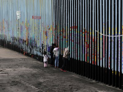 Une famille devant la barrière séparant le Mexique des Etats-Unis, le 16 janvier 2019 à Tijuana - Guillermo Arias [AFP/Archives]