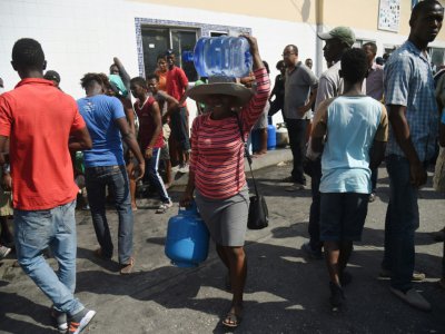 Des habitants de Port-au-Prince font la queue pour des bouteilles de gaz et des bidons d'eau, le 16 février 2019 en Haïti - HECTOR RETAMAL [AFP]
