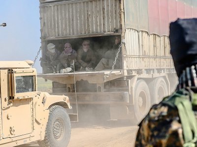Des combattants du groupe Etat islamique qui se sont rendus aux Forces démocratiques syriennes (FDS), sont transportés en camioin hors de Baghouz, le 20 février 2019 - Bulent KILIC [AFP]