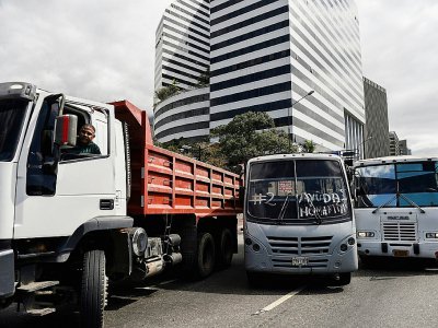 Des camions et autocar qui serviront à prendre livraison de l'aide humanitaire envoyée par les Etats-Unis et le Brésil, lors d'un rassemblement en soutien à l'opposant vénézuélien Juan Guaido, le 20 février 2019 à Caracas - Federico Parra [AFP]