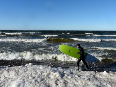 La surfeur Nikita Kononovich, 29 ans, entre dans les eaux glacées du golfe de Finlande près du village de Lipovo près de Saint-Petersbourg le 17 février 2019 - Olga MALTSEVA [AFP]