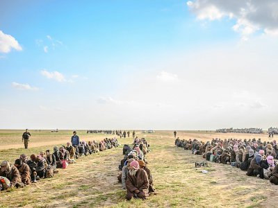 Soupçonnés d'appartenir au groupe jihadiste Etat islamique (EI), des hommes assis les uns derrière les autres attendent d'être fouillés par des forces arabo-kurdes, près de Baghouz dans l'est de la Syrie, le 22 février 2019 - Bulent KILIC [AFP/Archives]