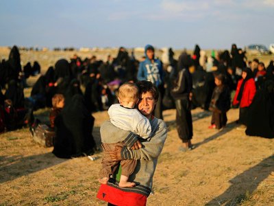 Des femmes et des enfants ayant fui Baghouz, dernier réduit du groupe jihadiste Etat islamique (EI) dans l'est de la Syrie, attendent d'être fouillés par les Forces démocratiques syriennes, dans le nord de la province syrienne de Deir Ezzor, le 22 fé - Delil SOULEIMAN [AFP/Archives]