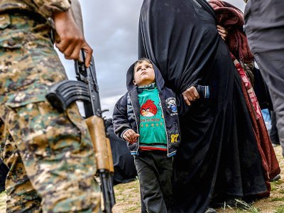 Un enfant regarde un combattant des Forces démocratiques syriennes après avoir quitté le dernier réduit du groupe Etat islamique à Baghouz, dans l'est syrien, le 27 février 2019 - Bulent KILIC [AFP]