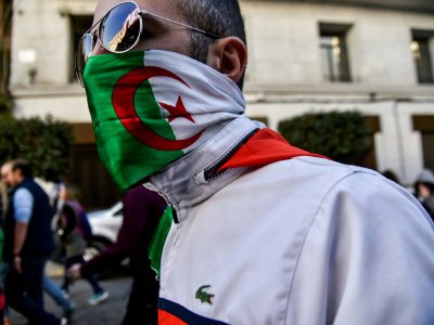 Manifestant  portant un drapeau algérien en guise de masque, pendant les manifestations à Alger contre un nouveau mandat du président  Bouteflika, le 1er mars 2019 - RYAD KRAMDI [AFP]