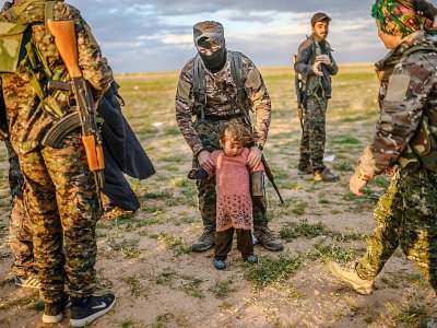 Un membre des Forces démocratiques syriennes tient une petite fille lors d'un contrôle de sécurité à un point de rassemblement près du village syrien de Baghouz, le 27 février 2019 - Bulent KILIC [AFP]