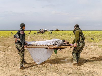 Des combattants des Forces démocratiques syriennes portent sur un brancard un homme blessé soupçonné d'appartenir au groupe Etat islamique, qui a quitté le dernier réduit de l'EI à Baghouz, dans l'est de la Syrie, le 5 mars 2019 - Bulent KILIC [AFP]