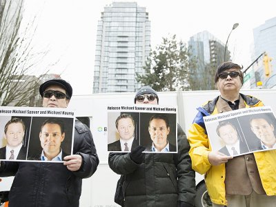 Des manifestants tiennent des photos de deux Canadiens interpellés en Chine, devant la Cour suprême de Vancouver, le 6 mars 2019 au Canada - Jason Redmond [AFP]