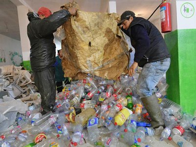 Des chiffonniersvident un sac de bouteilles et autres déchets plastique dans le local de l'association des Barbechas, le 10 janvier 2018 à Tunis - FETHI BELAID [AFP]