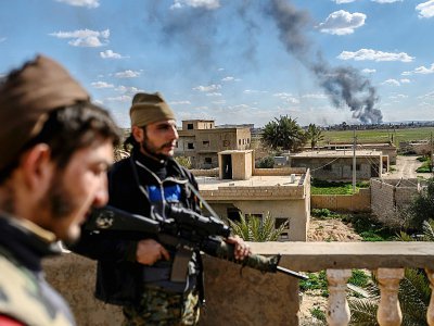 Des membres des Forces démocratiques syriennes (FDS) et au loin le village de Baghouz, dernier réduit du groupe Etat islamique bombardé, le 3 mars 2019 - Bulent KILIC [AFP]