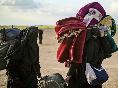 Des femmes croulant sous de lourds sacs à dos et baluchons fuient le dernier réduit du groupe Etat islamique (EI) à Baghouz dans l'est de la Syrie, le 6 mars 2019 - Delil souleiman [AFP]