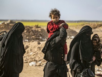 Une femme porte un enfant après avoir fui le dernier réduit du groupe Etat islamique (EI) à Baghouz, dans l'est de la Syrie, le 5 mars 2019 - Delil SOULEIMAN [AFP/Archives]