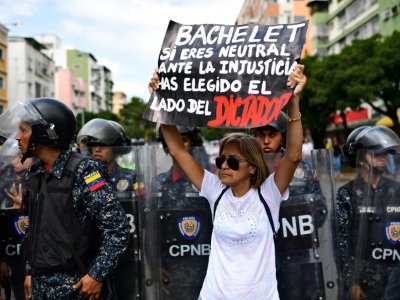 Une partisane de Juan Guaido manifeste à Caracas le 9 mars 2019 avec une banderole disant "Bachelet, si tu restes neutre face à l'injustice, tu as pris le parti du dictateur", adressée à Michelle Bachelet, Haut-Commissaire de l'ONU aux droits de l'ho - RONALDO SCHEMIDT [AFP]