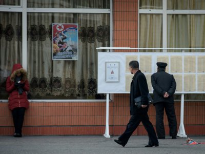Des passants devant des listes électorales, le 9 mars 2019 à Pyongyang - Ed JONES [AFP]